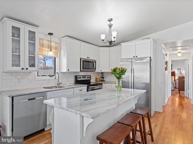 kitchen with stainless steel appliances, decorative light fixtures, sink, and white cabinets