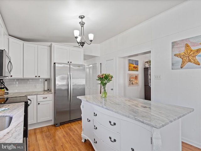 kitchen featuring light hardwood / wood-style flooring, stainless steel appliances, a center island, white cabinets, and decorative light fixtures