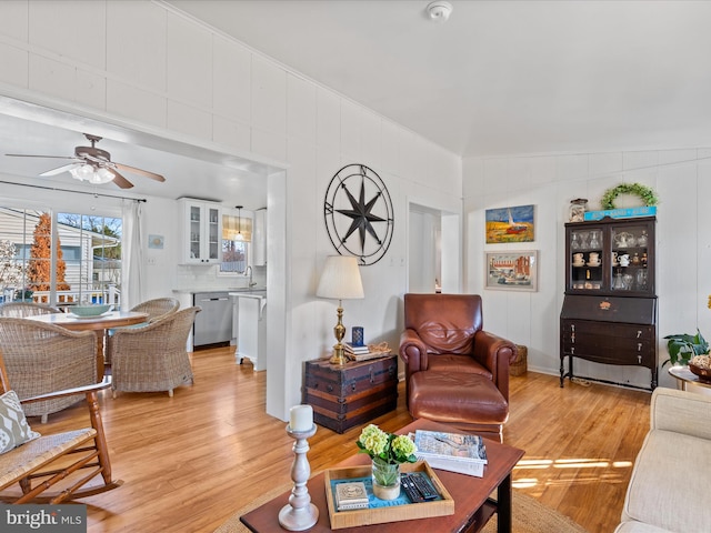 living room featuring ceiling fan, sink, and light wood-type flooring