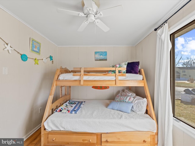 bedroom with crown molding, wood-type flooring, and ceiling fan