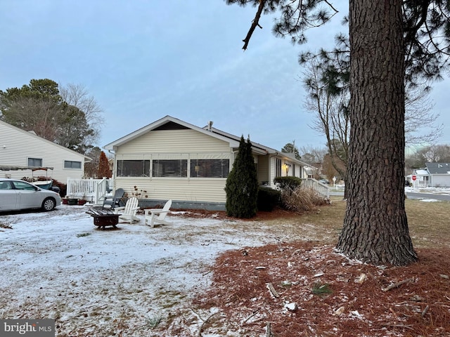 view of snow covered exterior with a sunroom and a fire pit