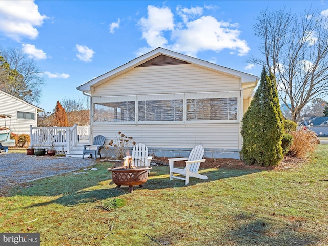 back of house with a wooden deck, a yard, a sunroom, and an outdoor fire pit