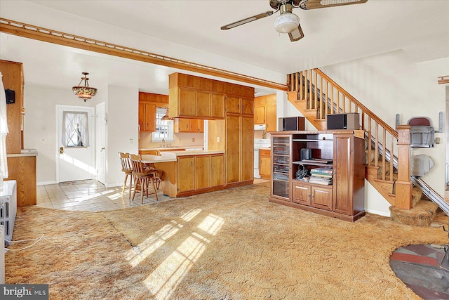 kitchen featuring pendant lighting, ceiling fan, a kitchen breakfast bar, light carpet, and kitchen peninsula