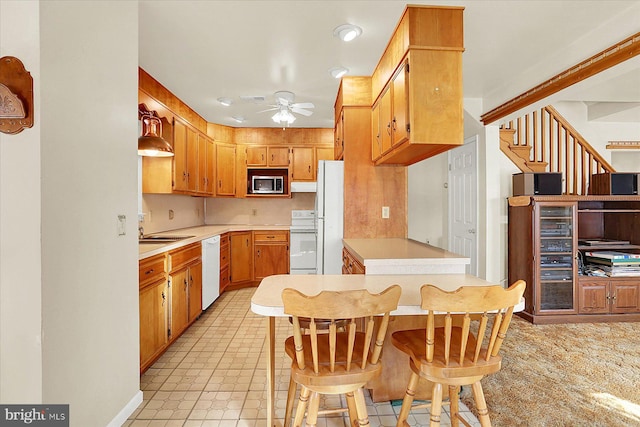 kitchen with white appliances, a breakfast bar area, ceiling fan, decorative light fixtures, and kitchen peninsula