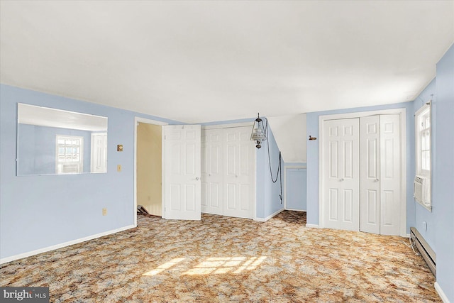 unfurnished bedroom featuring multiple closets, carpet, and a baseboard heating unit