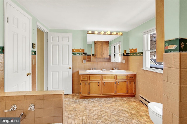 bathroom with baseboard heating, tile walls, vanity, tile patterned floors, and toilet