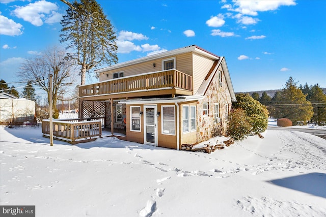 snow covered house with a wooden deck and a balcony