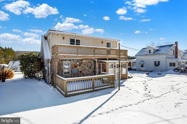 snow covered property with a wooden deck and a balcony