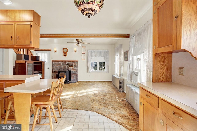 kitchen featuring radiator heating unit, a wealth of natural light, light colored carpet, and a kitchen breakfast bar