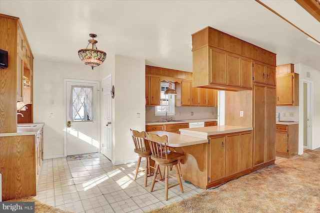 kitchen featuring decorative light fixtures, dishwasher, sink, a kitchen breakfast bar, and kitchen peninsula