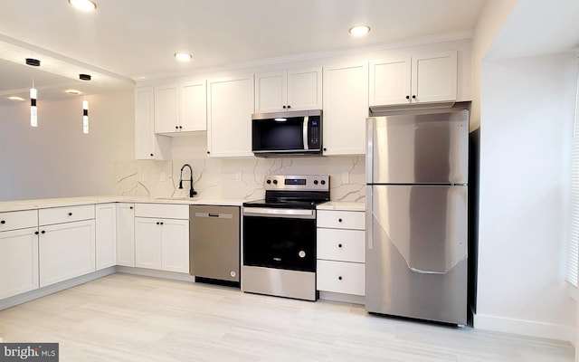 kitchen featuring white cabinetry, sink, pendant lighting, and stainless steel appliances