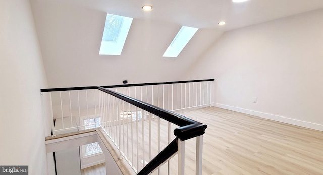 staircase featuring wood-type flooring and lofted ceiling with skylight