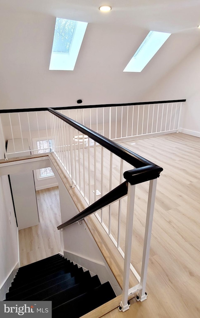 stairway with wood-type flooring and lofted ceiling