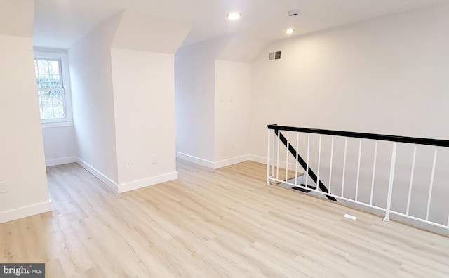 spare room featuring vaulted ceiling and light wood-type flooring