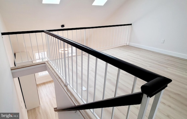 stairs with hardwood / wood-style flooring and a skylight