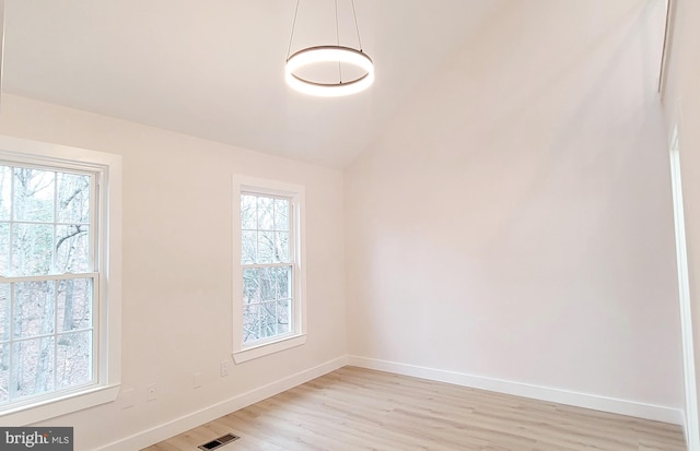 spare room with light hardwood / wood-style flooring, plenty of natural light, and lofted ceiling