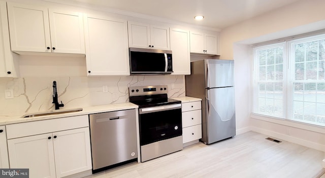 kitchen featuring light stone counters, sink, stainless steel appliances, and white cabinets