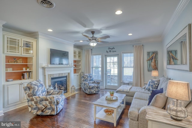 living room with crown molding, a fireplace, dark hardwood / wood-style flooring, and built in features