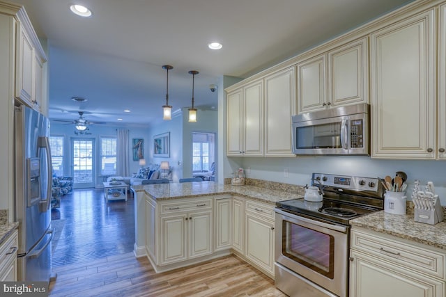 kitchen featuring decorative light fixtures, light hardwood / wood-style flooring, appliances with stainless steel finishes, light stone countertops, and cream cabinets