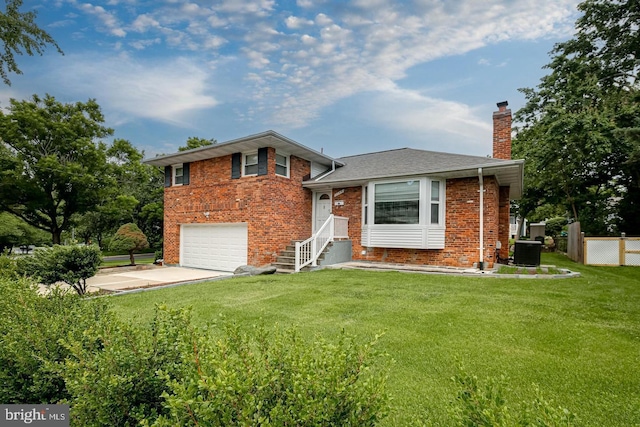 tri-level home featuring a garage, a front yard, and central air condition unit