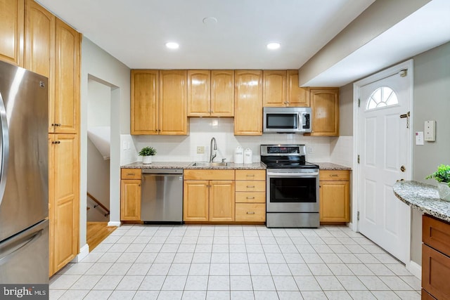 kitchen featuring sink, light stone counters, tasteful backsplash, light tile patterned floors, and stainless steel appliances