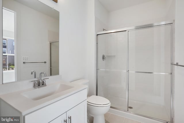 bathroom with tile patterned flooring, vanity, a shower with shower door, and toilet