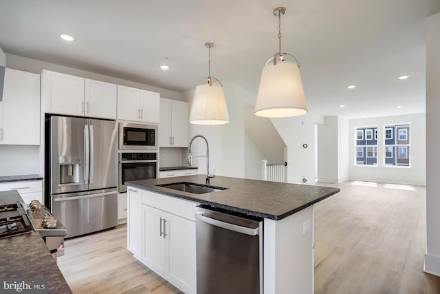 kitchen with tasteful backsplash, sink, white cabinets, hanging light fixtures, and stainless steel appliances