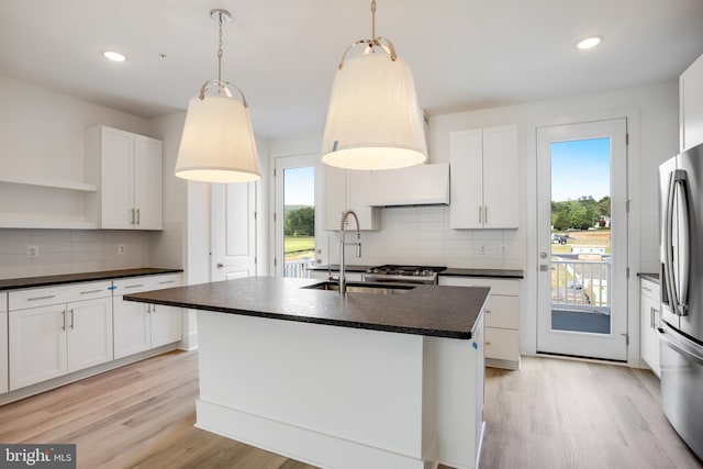 kitchen with an island with sink, pendant lighting, and white cabinets