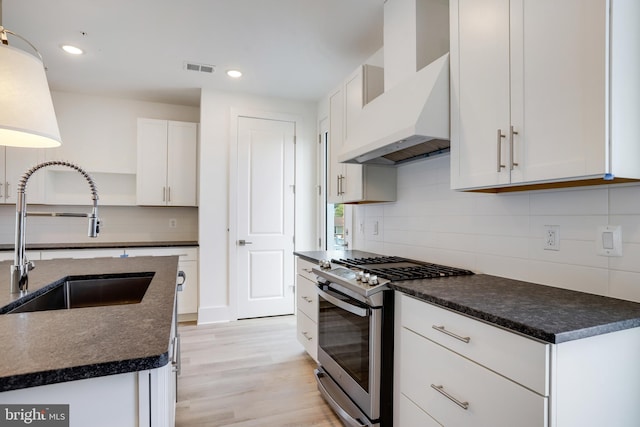 kitchen with sink, light hardwood / wood-style flooring, white cabinetry, custom range hood, and gas range