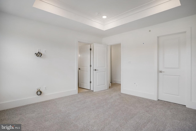 unfurnished bedroom featuring light carpet and a tray ceiling