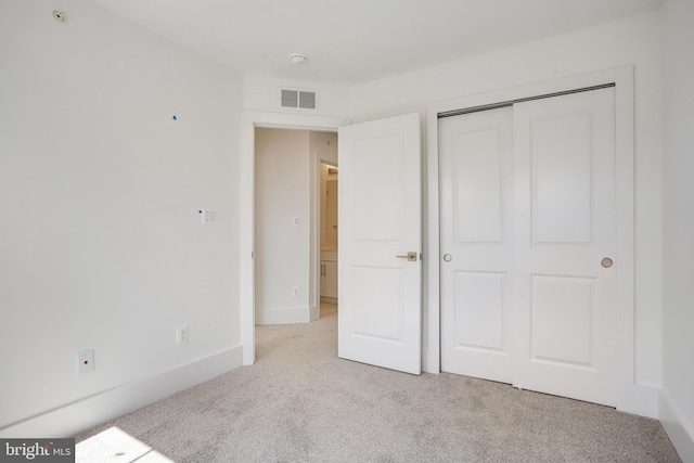 unfurnished bedroom featuring a closet and light carpet