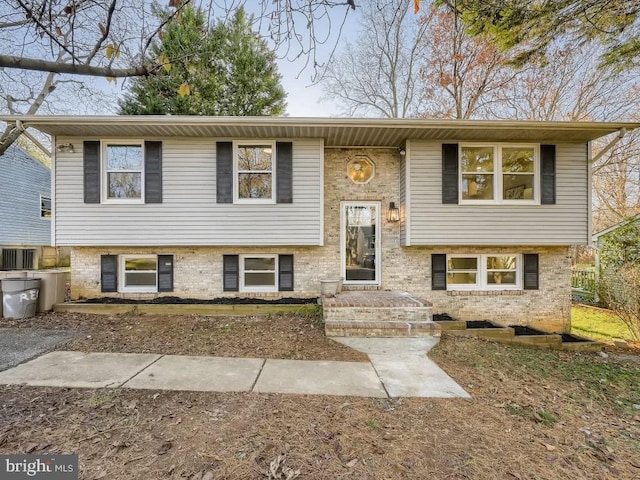 split foyer home featuring brick siding and cooling unit