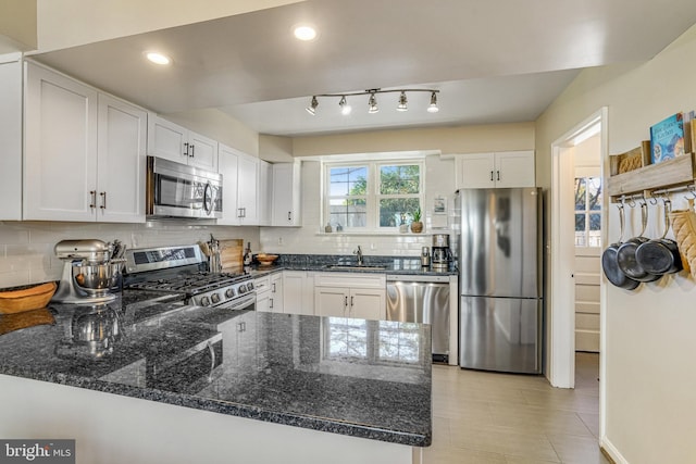 kitchen with white cabinetry, sink, kitchen peninsula, and appliances with stainless steel finishes