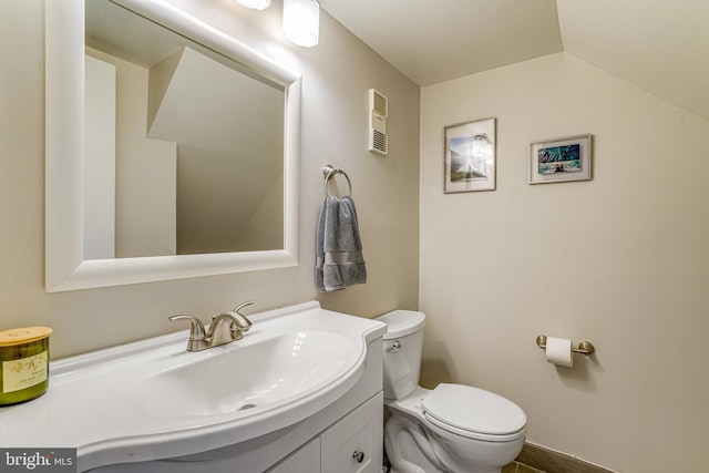 bathroom featuring vanity, toilet, and vaulted ceiling