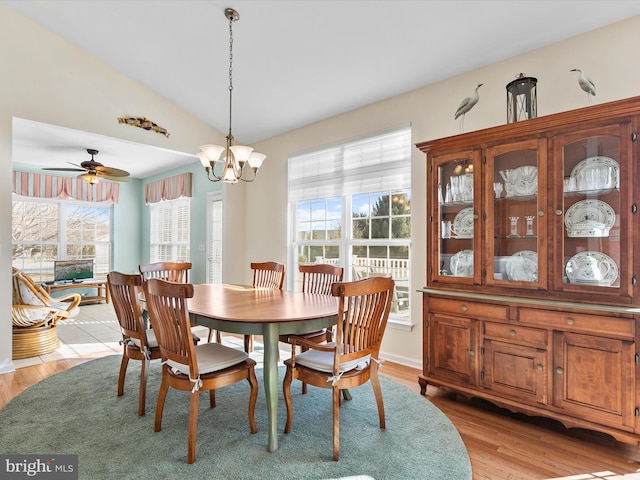 dining room featuring a notable chandelier, vaulted ceiling, and light wood-type flooring