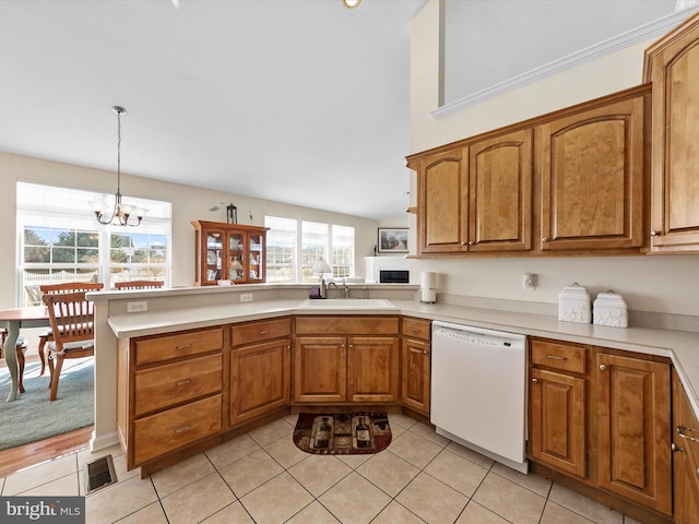 kitchen with pendant lighting, sink, white dishwasher, light tile patterned flooring, and kitchen peninsula