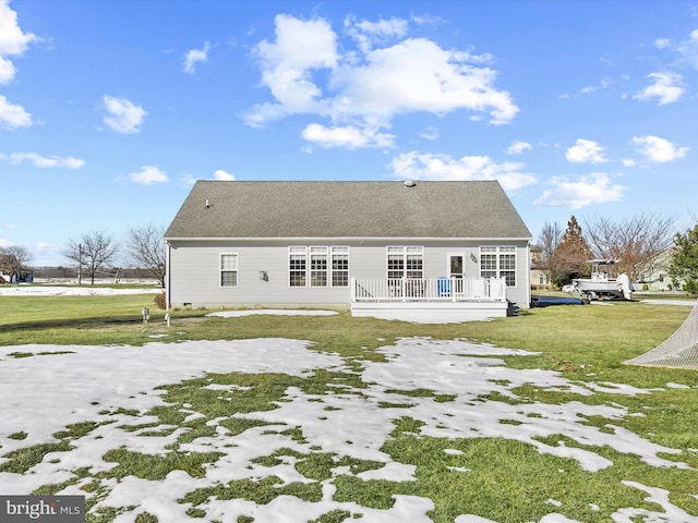 rear view of property featuring a wooden deck and a lawn