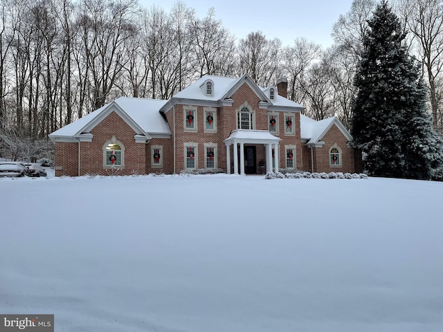 georgian-style home with a chimney and brick siding