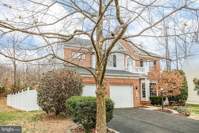 view of front of home with brick siding, driveway, an attached garage, and fence