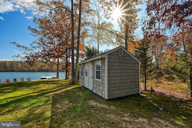 view of outdoor structure with a water view and a lawn