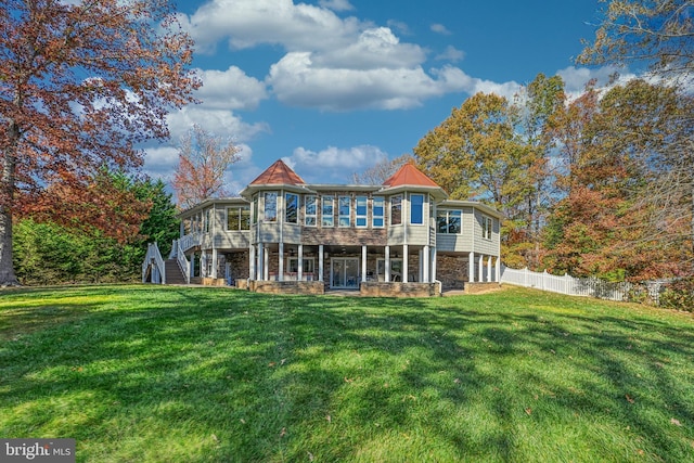 rear view of property with a deck, a sunroom, and a lawn