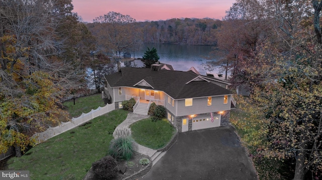 view of front facade with a garage, a water view, and a lawn