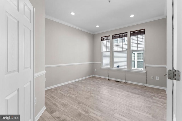 spare room with baseboards, light wood-style flooring, and crown molding