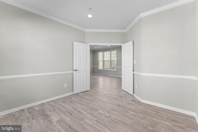 spare room with ornamental molding, light wood finished floors, and baseboards