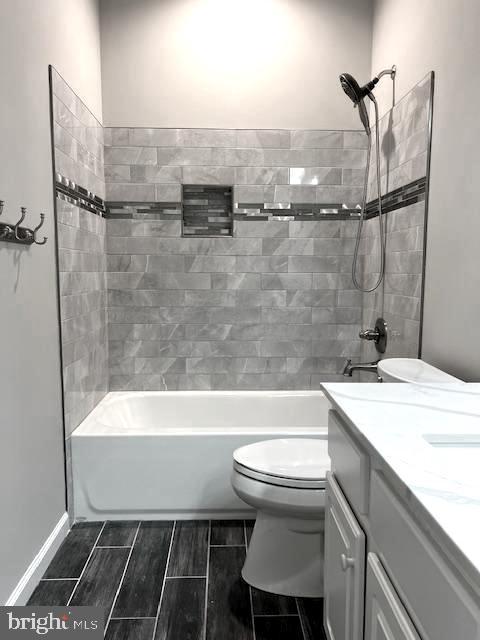 full bathroom featuring toilet, vanity, bathing tub / shower combination, and wood tiled floor