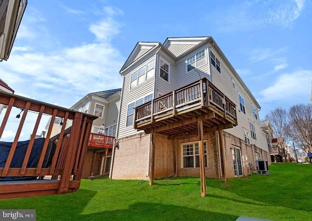 rear view of house with cooling unit, brick siding, a yard, and a wooden deck