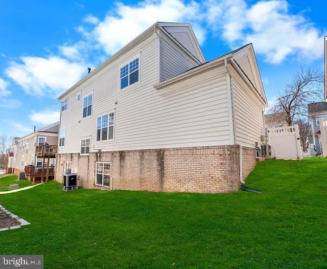 back of house with central AC, fence, a lawn, and brick siding