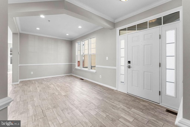 foyer featuring light wood-style floors, baseboards, visible vents, and crown molding