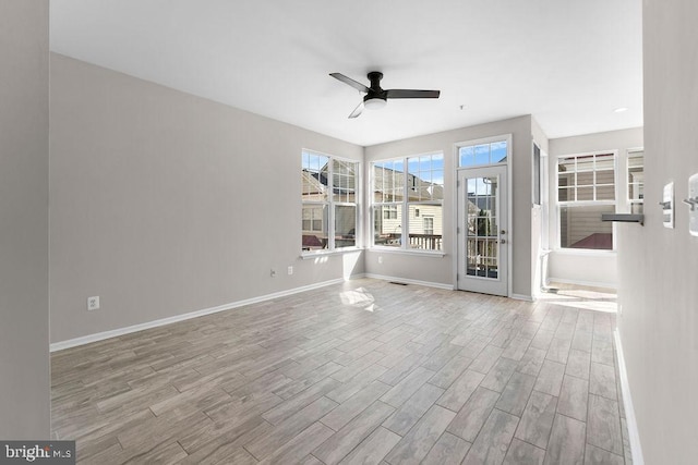 unfurnished living room with light wood-style floors, baseboards, and a ceiling fan