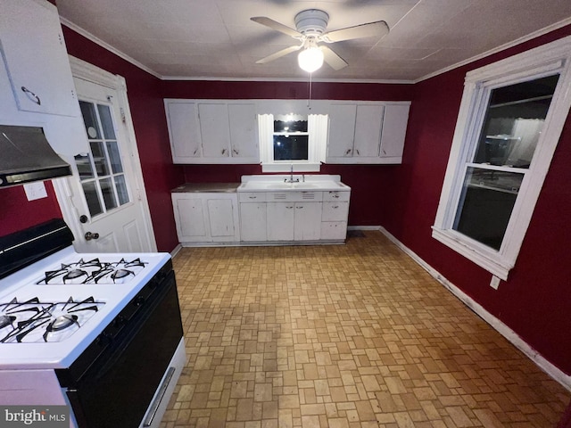 kitchen with crown molding, ceiling fan, gas range, and white cabinets